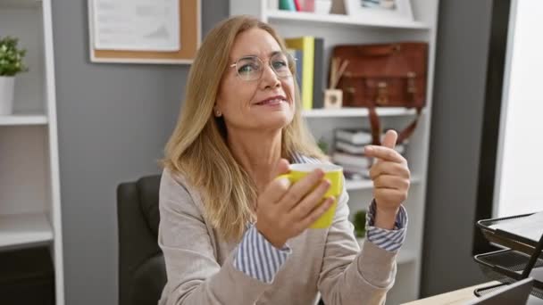 Dojrzałe Blondynka Kobieta Gestem Kciuki Górę Trzymając Kubek Biuro Ustawienie — Wideo stockowe