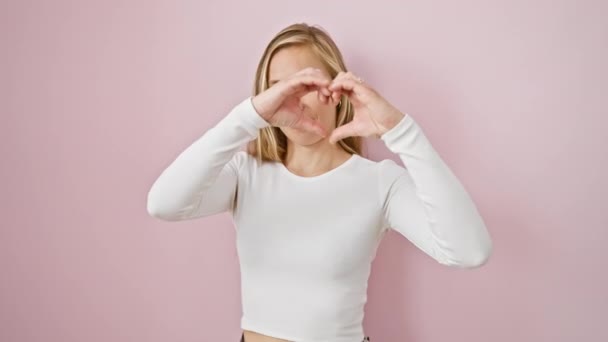 Urocza Blondynka Wyrażająca Miłość Symbolem Serca Nad Żywym Różowym Odizolowanym — Wideo stockowe