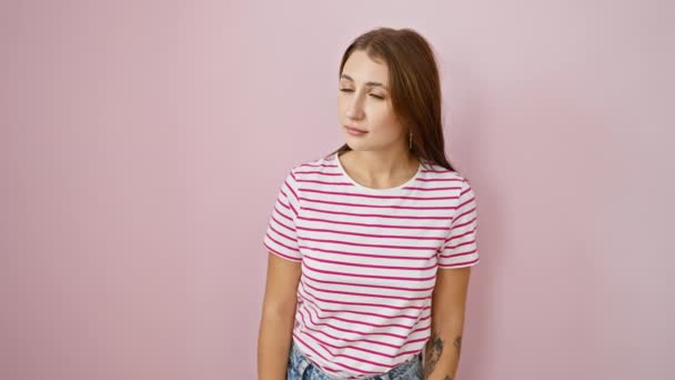 驚くべき若いブルネットの少女が先にストライプシャツをポイントし 目に見えないものに魅了され 孤立したピンクの背景の上に広く開きます — ストック動画