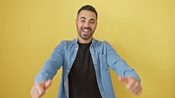 デニムシャツの陽気な若いヒスパニック系男性は喜んで勝利を祝い 親指を上げました 黄色の背景に完全に隔離された勝者のジェスチャー — ストック動画
