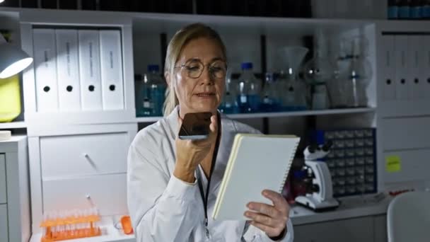 Donna Matura Scienziata Utilizzando Smartphone Prendendo Appunti Moderno Ambiente Laboratorio — Video Stock