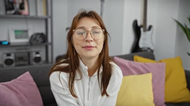 Egy Alkalmi Fiatal Szemüveggel Mosolyog Egy Modern Nappaliban Színes Párnákkal — Stock videók