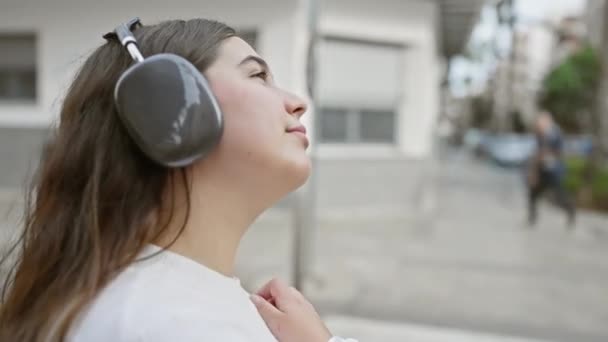 一个年轻的惊慌失措的女人喜欢在城市街道上戴耳机的音乐 — 图库视频影像