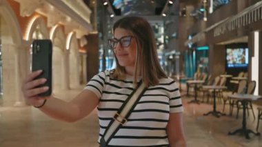 Genç bir kadın lüks bir yolcu gemisinde selfie çekiyor, modern seyahat ve tatil atmosferini somutlaştırıyor..