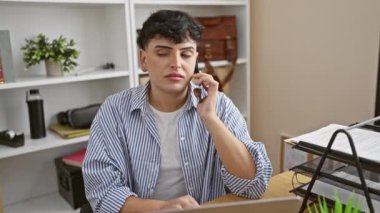 Modern ofis ortamında akıllı telefon ve dizüstü bilgisayarla birden fazla iş yapan genç adam profesyonellik ve bağlantı gösteriyor.