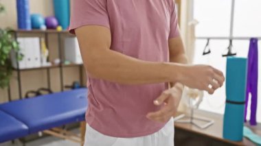 Genç bir İspanyol adam fizik tedavi kliniğinde kolunu uzatıyor. İyileşme ya da egzersiz öneriyor..