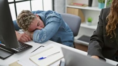 Modern ofiste odaklanmış bir kadının yanında uyuyan aşırı çalışan adam yorgunluk ve takım çalışması tasvir ediyor..