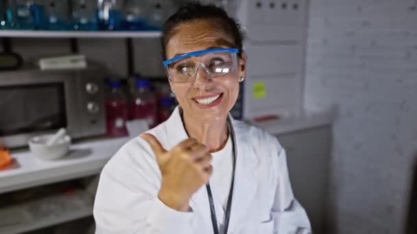 Cheerful Middle Age Hispanic Woman Scientist Safety Glasses Happily Pointing — Stock Video