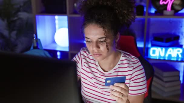 夜に自宅でゲームしながらクレジットカードを使用してカーリーヘアを持つ若い女性 — ストック動画