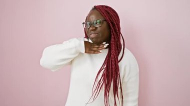 Pembe arka planda örgü ve gözlüklü gülümseyen Afrikalı bir kadının portresi..