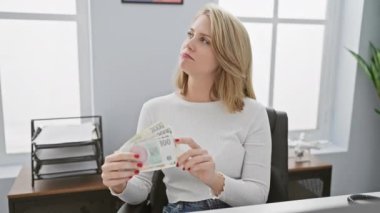 Düşünceli genç bir kadın modern ofis ortamında Czech Koruna banknotlarını inceliyor, finans, para ve ekonomiyi yansıtıyor.