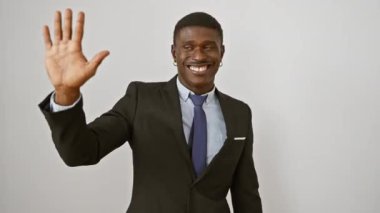 Neşeli Afro-Amerikalı takım elbiseli adam kendine güvenerek ayakta duruyor ve beş numarayı işaret ediyor ve beyaz soyutlanmış arka plana gülümsüyor.