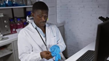 Eldiven giyen Afrikalı Amerikalı bilim adamı laboratuarda araştırma yapmaya hazırlanıyor..