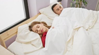 Bir kadın ve bir erkek rahat bir yatak odasında, aşk, dinlenme ve ilişki yakınlığı temaları öneriyor..