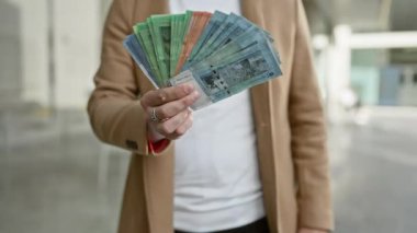 Bir adam, maliye, seyahat ve iş kavramlarını gösteren şehir ortamında Malezya halkalarının yayılmasını elinde tutar..