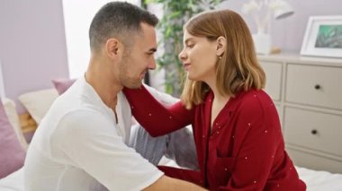 Bir erkek ve bir kadın, sıcak bir yatak odasında samimi bir aşk sergilerken, bir yatakta alınlarına şefkatle dokunuyor..