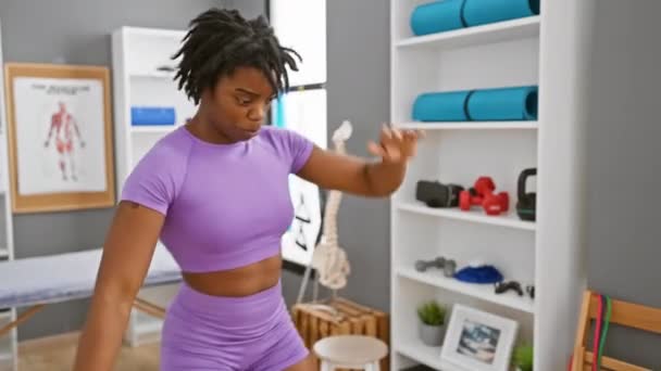 紫色のアトリスチュールのドレッドロックを持つ若い女性は 理学療法クリニックで着用します — ストック動画