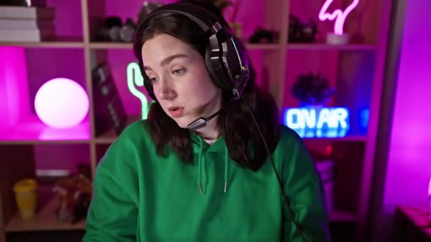 Young Woman Wearing Headphones Neon Lit Gaming Room Looks Focused — Stock Video