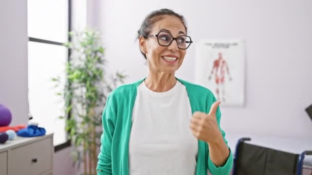 Radosna Latynoska Kobieta Średnim Wieku Fizjoterapeutka Stojąca Klinice Odwykowej Ufnością — Wideo stockowe