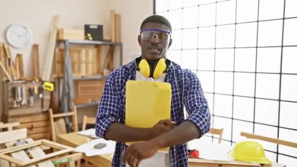 Hombre Seguro Con Gafas Seguridad Auriculares Sujetando Portapapeles Brillante Taller — Vídeos de Stock