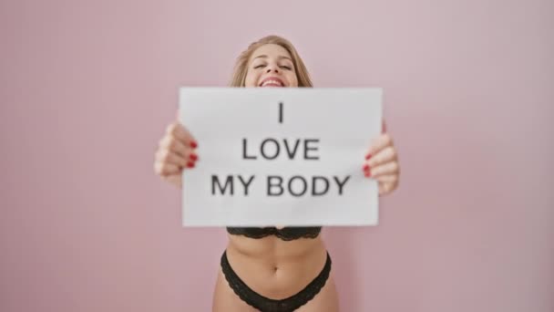 自信的女人在粉红孤立的背景下 举着一个标志 庆祝身体的积极向上 — 图库视频影像