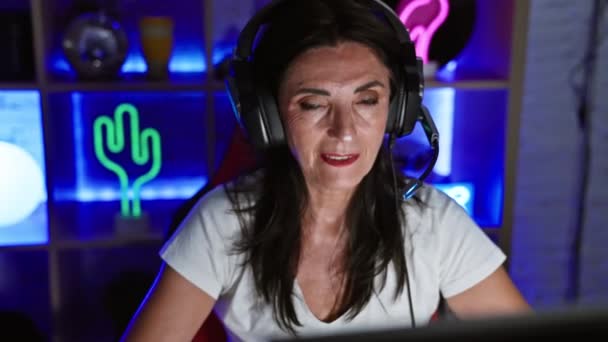 Sorrindo Mulher Hispânica Sênior Usando Fones Ouvido Uma Sala Jogos — Vídeo de Stock