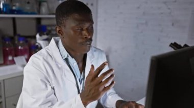 Modern bir laboratuvar ortamında bilgisayar ekranındaki verileri analiz eden odaklanmış bir siyah adam.