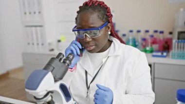 Laboratuvarda mikroskopla numuneleri inceleyen Afrikalı kadın bilim adamı.