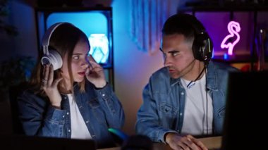 Bir adam ve bir kadın, oyun oynuyorlar, kulaklık takıyorlar geceleri neon ışıklı bir ofiste..