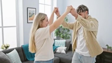 Neşeli bir erkek ve kadın, sıcak bir oturma odasında dans eder, parlak bir evde sevgi ve mutluluk ifade eder..