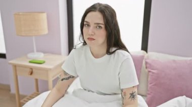 Pijamalı genç bir rock yıldızı. Elleriyle taş işareti yapıyor. Yatak odasında oturuyor.