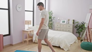 Genç adam parlak bir yatak odasında denge egzersizleri yapıyor, spor, sağlık ve modern bir yaşam tarzı sergiliyor..