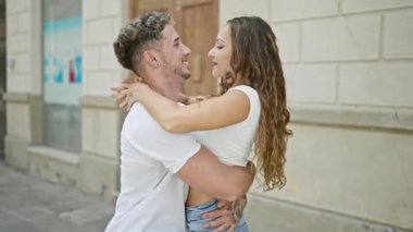 Neşeli bir çift, güneşli bir şehir sokağında, kendiliğinden oluşan romantik bir anı sevgiyle kucaklıyor..