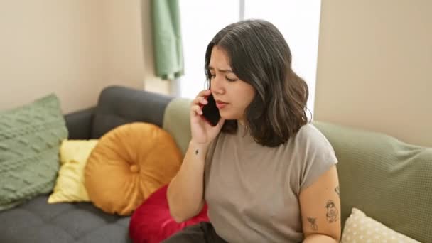 一位忧心忡忡的年轻成年女子在一间有枕头的五颜六色的客厅里用电话交谈 — 图库视频影像