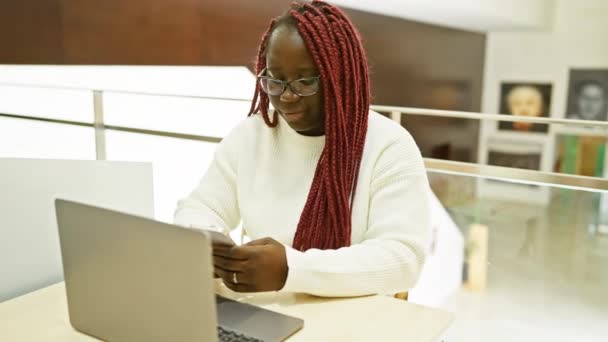 Улыбающаяся Африканская Американка Косичками Использующая Смартфон Ноутбук Современном Офисе — стоковое видео