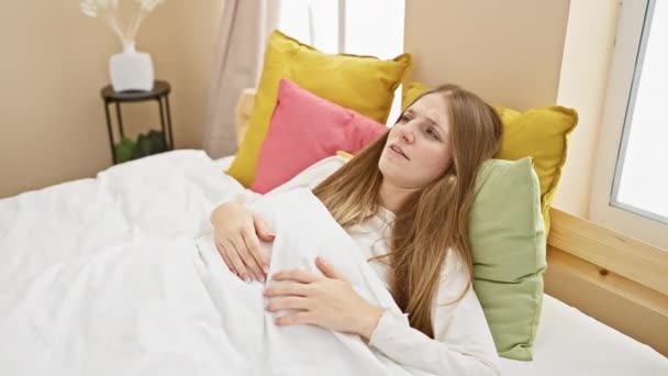 Şaşırmış Genç Sarışın Kadın Pijama Giyiyor Yatak Odasında Oturuyor Şaşırmış — Stok video