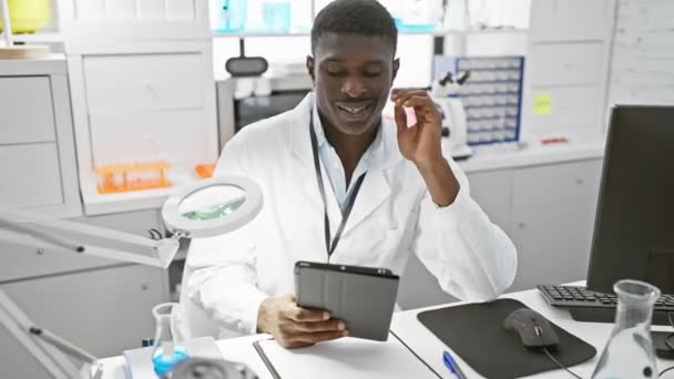 笑顔のアフリカ人男性がタブレット 拡大鏡 コンピュータ機器を備えた研究室で働いています — ストック動画