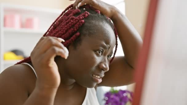 Een Gefocuste Zwarte Vrouw Met Rode Vlechten Styling Haar Haar — Stockvideo