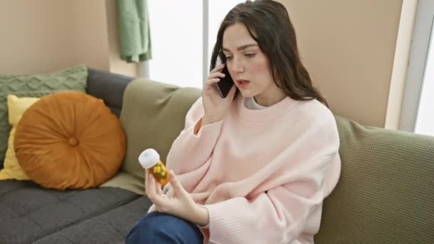 Mujer Joven Preocupada Suéter Rosa Teléfono Sosteniendo Frasco Medicina Interior — Vídeos de Stock