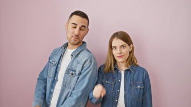 Kot gömlekli mutlu çift, heyecanlı bir şekilde zekice bir fikirle parmağını kaldırıyor, izole edilmiş pembe arka planda bir numara olarak zafer kazanıyor.