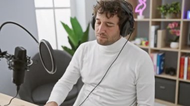 Havalı İspanyol adam radyo stüdyosunda kulaklık takarak meditasyon yapıyor. Destansı zen ve yoga füzyon konsepti.