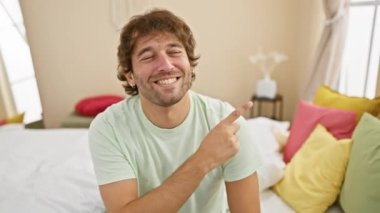 Neşeli beyaz bir adam, mutlu bir sırıtış sergiliyor, yatak odasını işaret ediyor! Doğal titreşimli sallanan pijamalar.!
