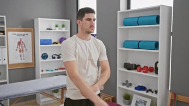 Young hispanic man stretching in a modern rehab clinic.