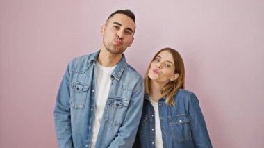 Kot gömlekli güzel bir çift, kameraya seksi bir öpücük üflerken küstah görünüyorlar, pembe izole bir arka planda..