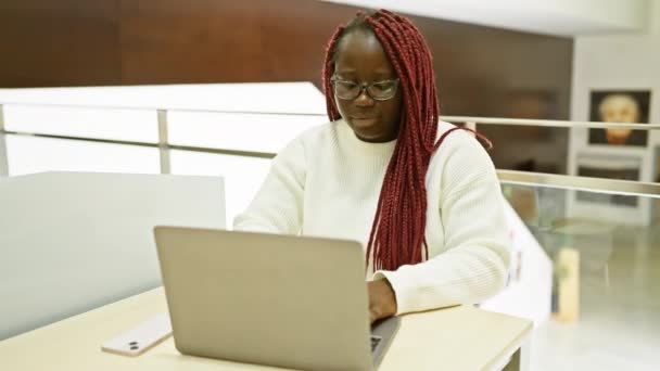 Αφροαμερικανή Γυναίκα Κοτσίδες Που Εργάζεται Φορητό Υπολογιστή Στο Σύγχρονο Εσωτερικό — Αρχείο Βίντεο