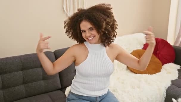 自信を持って 幸せなヒスパニック女性は 自宅でソファーで自分自身を誇らしげに指摘しています — ストック動画