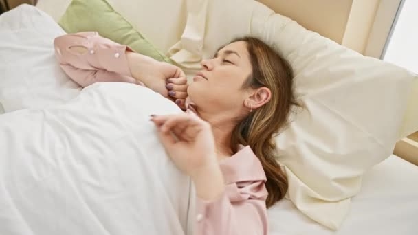 明るく明るい寝室で目覚め 朝の新鮮さを感じるベッドに伸びている若い女性 — ストック動画