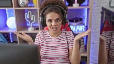 Kıvırcık saçlı, kafası karışık İspanyol bir kız, oyun odasında ellerini havaya kaldırmış, 'Bilmiyorum' yüzüyle kuşkuyla ve güzel, şaşkın duygularla dolu..