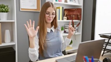 Ofisteki neşeli sarışın iş kadını, yedi numarayı gösterip, parmaklarını havaya kaldırıyor.