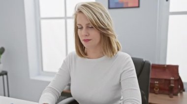 Modern ofis ortamında rahatsız olan genç bir sarışın kadın çeşitli duruşlarda boyun ağrısını tasvir ediyor..